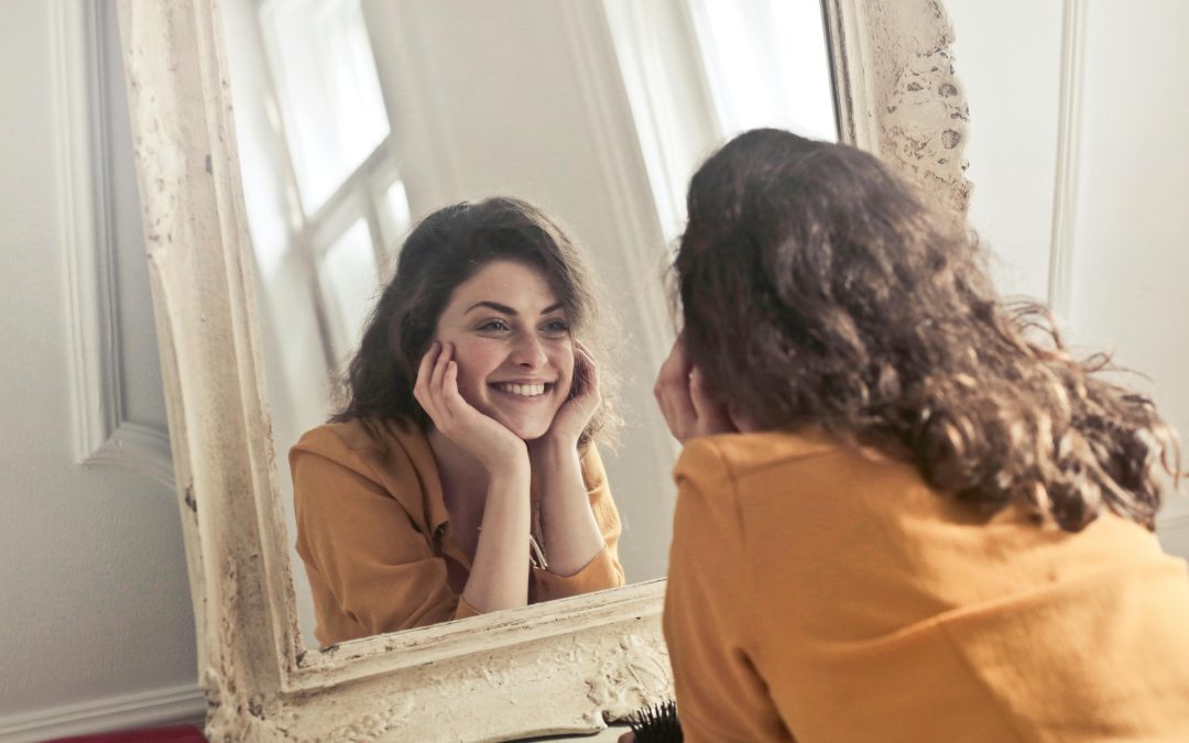 Smiling woman looking in mirror after digestive health and immune boost treatment in Victoria BC